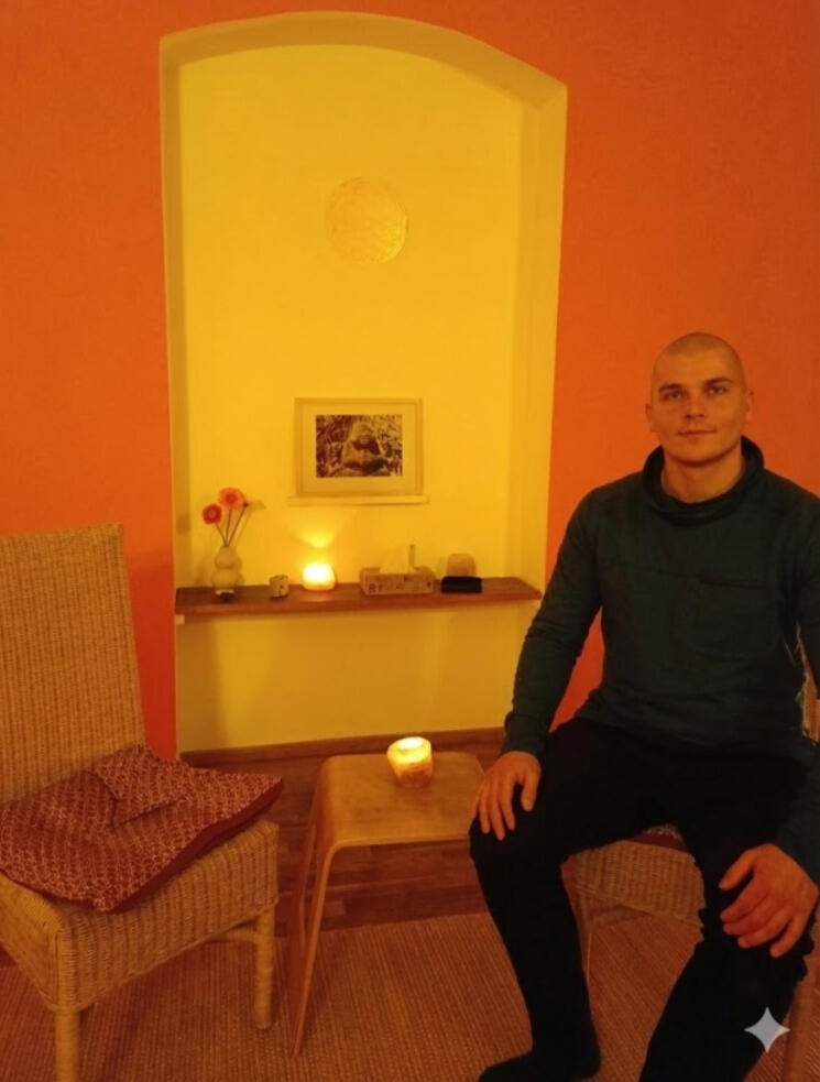 Coaching bei Dennis Jahnke Dennis Jahnke sitzt entspannt in seinem warm orange beleuchteten Praxisraum in Berlin auf einem Korbstuhl, in bereit für ein Gespräch.